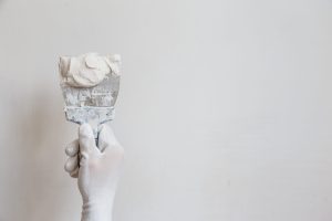 Worker in white gloves performs plastering of the walls of the room